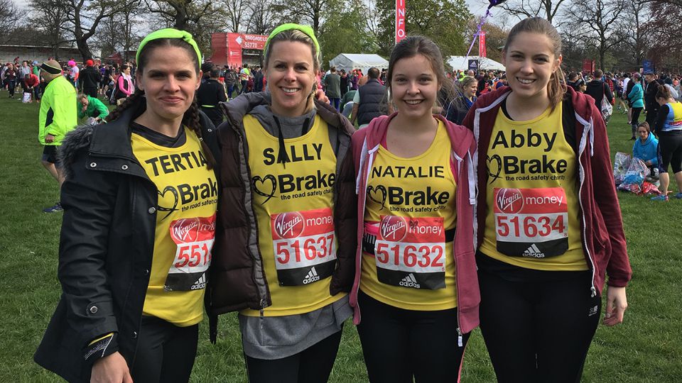 Four standing runners in yellow vests