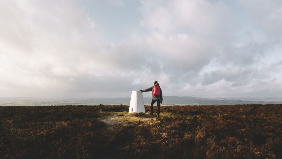 Walker standing next to a trig point