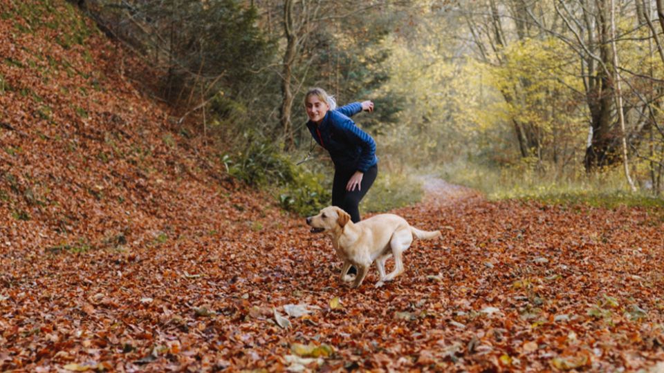 Woman running with dog in the woods