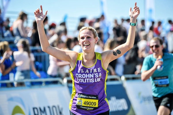 Happy woman finishing Brighton Marathon in a C&C vest