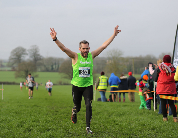 A Gut Buster runner raises his arms on the finish line