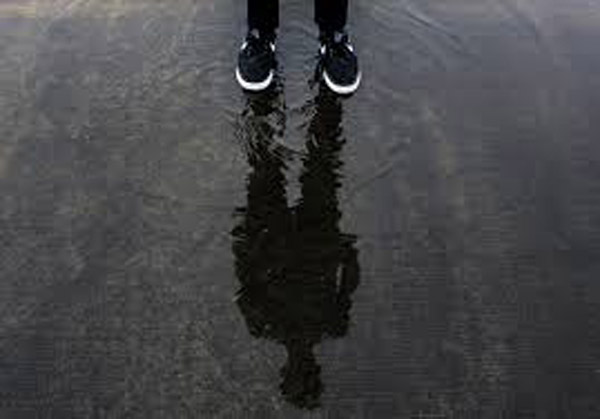 Foot and ankle shot of runner with full shadow in puddle